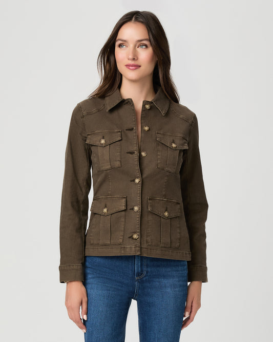 A woman modeling a dark brown utility jacket with four front flap pockets and gold-tone buttons, paired with blue jeans, against a light gray studio background.