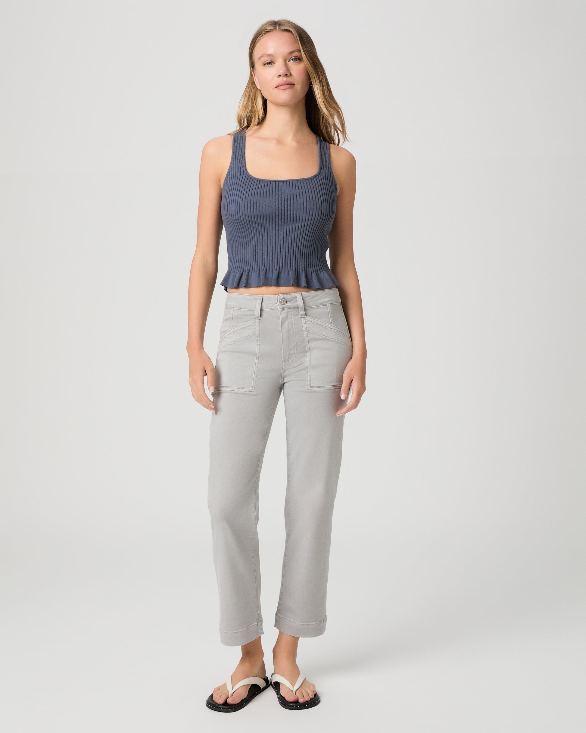 Woman wearing a blue top and gray pants on a white background