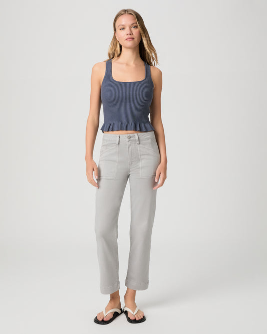 Woman wearing a blue top and gray pants on a white background