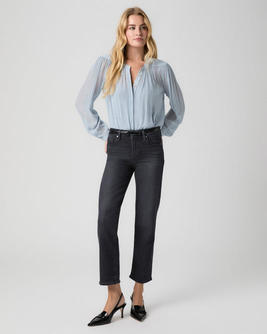 Model standing facing forward, hands resting on her hips, wearing a sheer light blue button-front blouse tucked into Mason Ankle Straight Jeans in Ink Black and black patent slingback heels