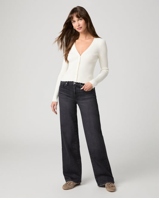 Woman in white top and black pants against a white background