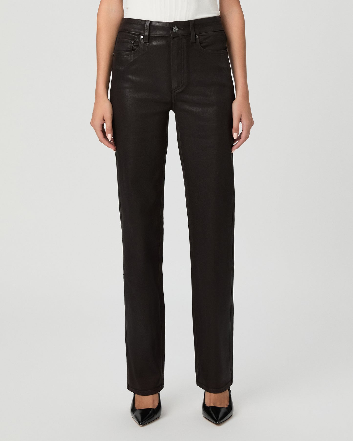 A woman modeling an off-the-shoulder white top and black straight-leg jeans against a light gray studio background.