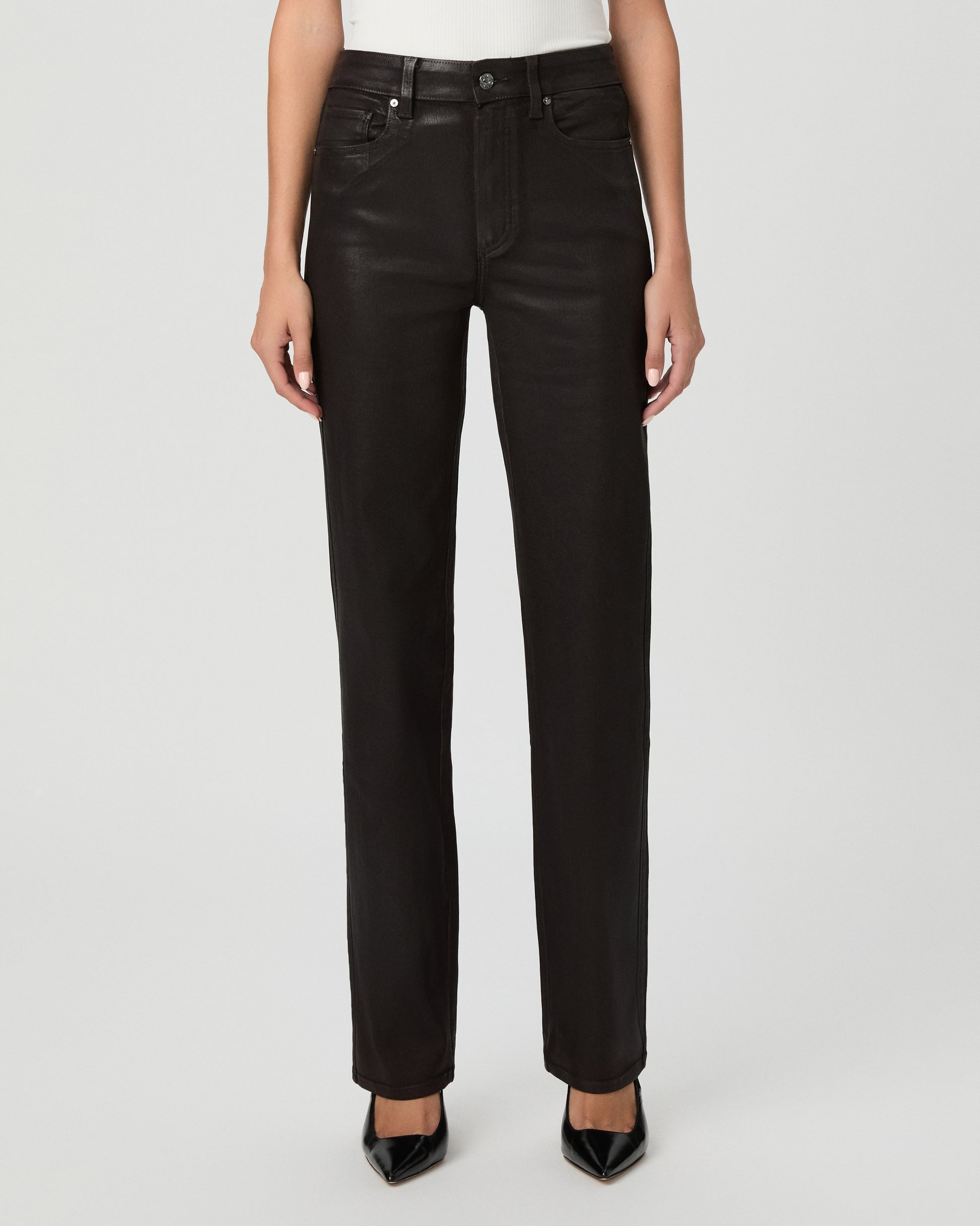 A woman modeling an off-the-shoulder white top and black straight-leg jeans against a light gray studio background.