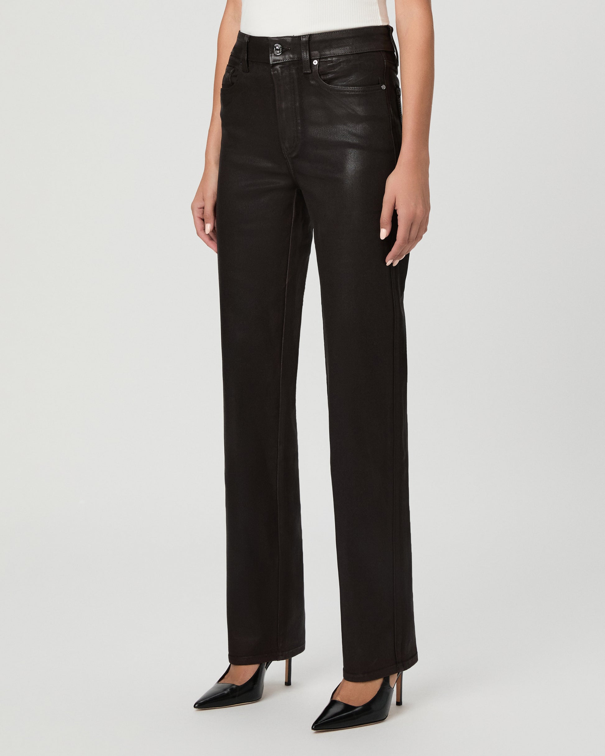 A woman modeling an off-the-shoulder white top and black straight-leg jeans against a light gray studio background.