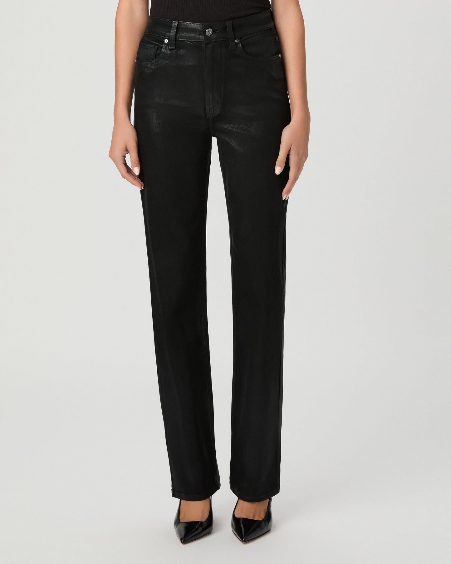 A woman modeling a black off-the-shoulder top and black high-waisted straight-leg jeans against a light gray studio background.