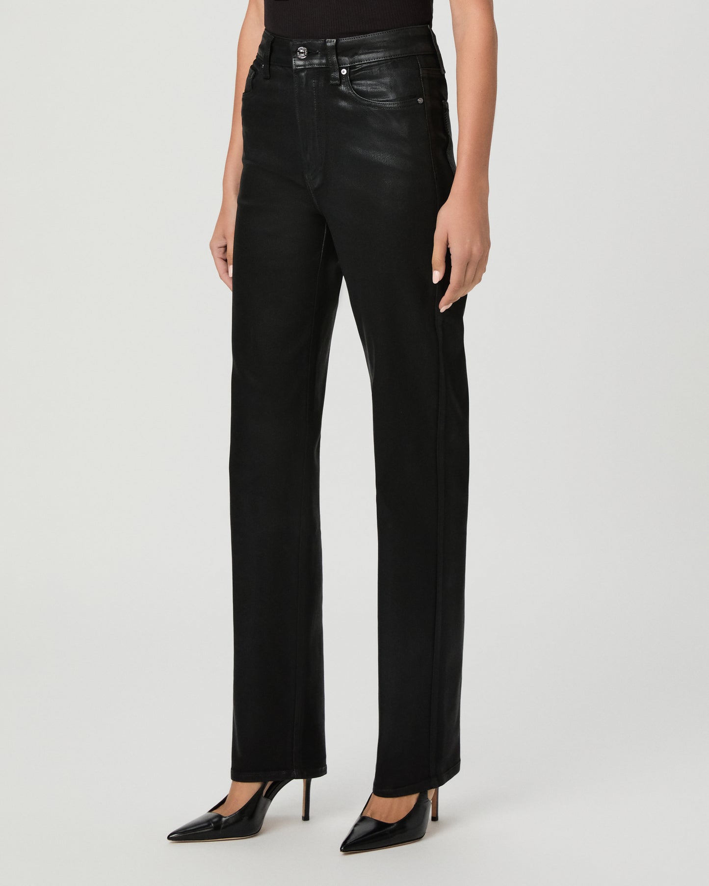 A woman modeling a black off-the-shoulder top and black high-waisted straight-leg jeans against a light gray studio background.