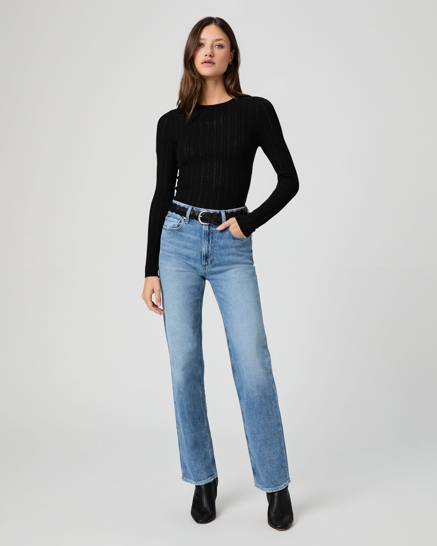 Woman wearing a black top and light blue jeans on a white background