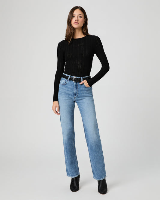Woman wearing a black top and light blue jeans on a white background