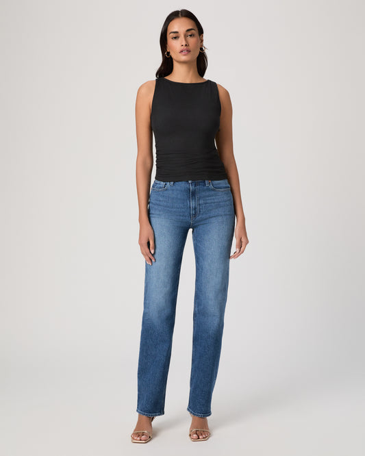 Woman wearing a black sleeveless top and blue jeans on a white background