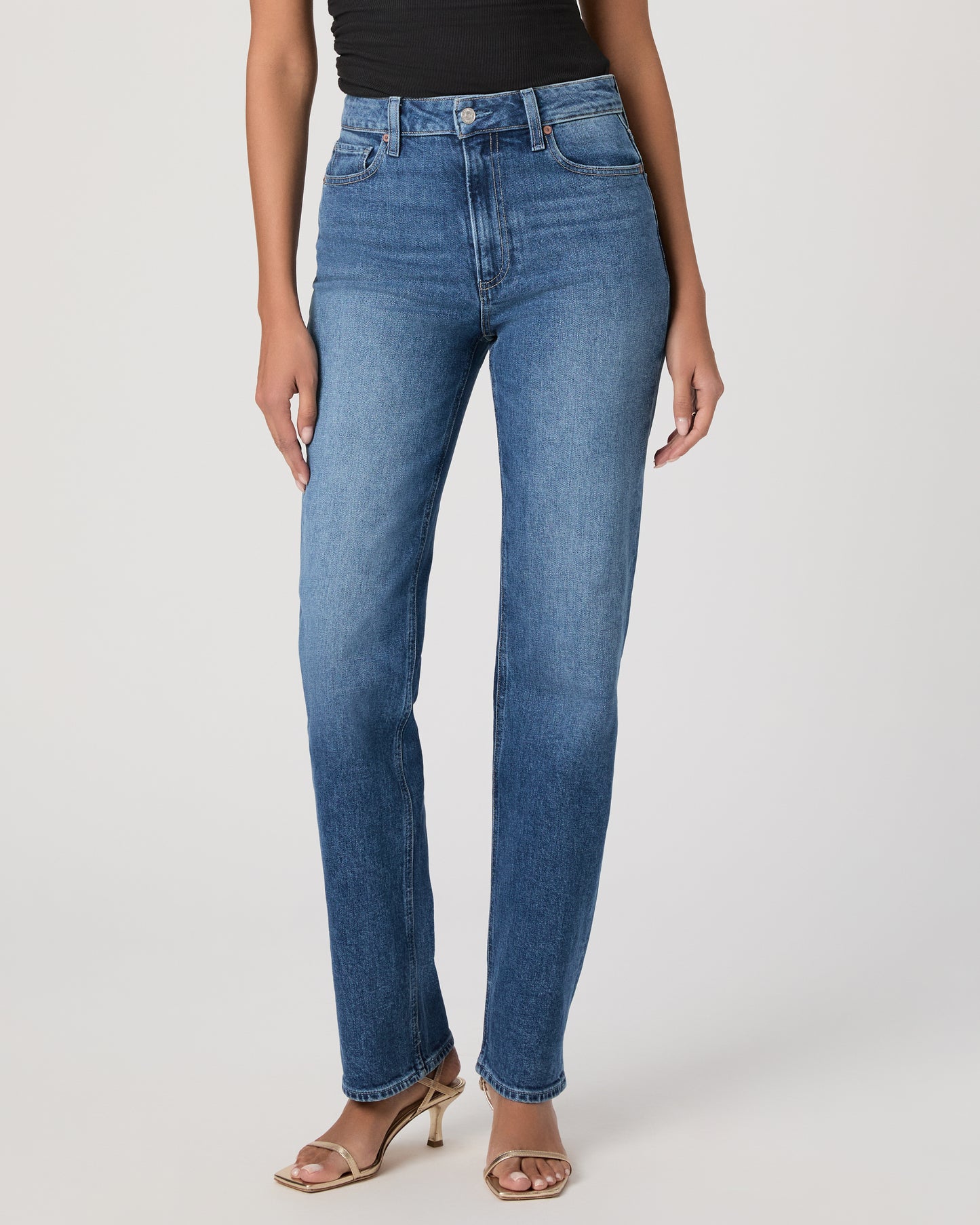 Woman wearing a black sleeveless top and blue jeans on a white background