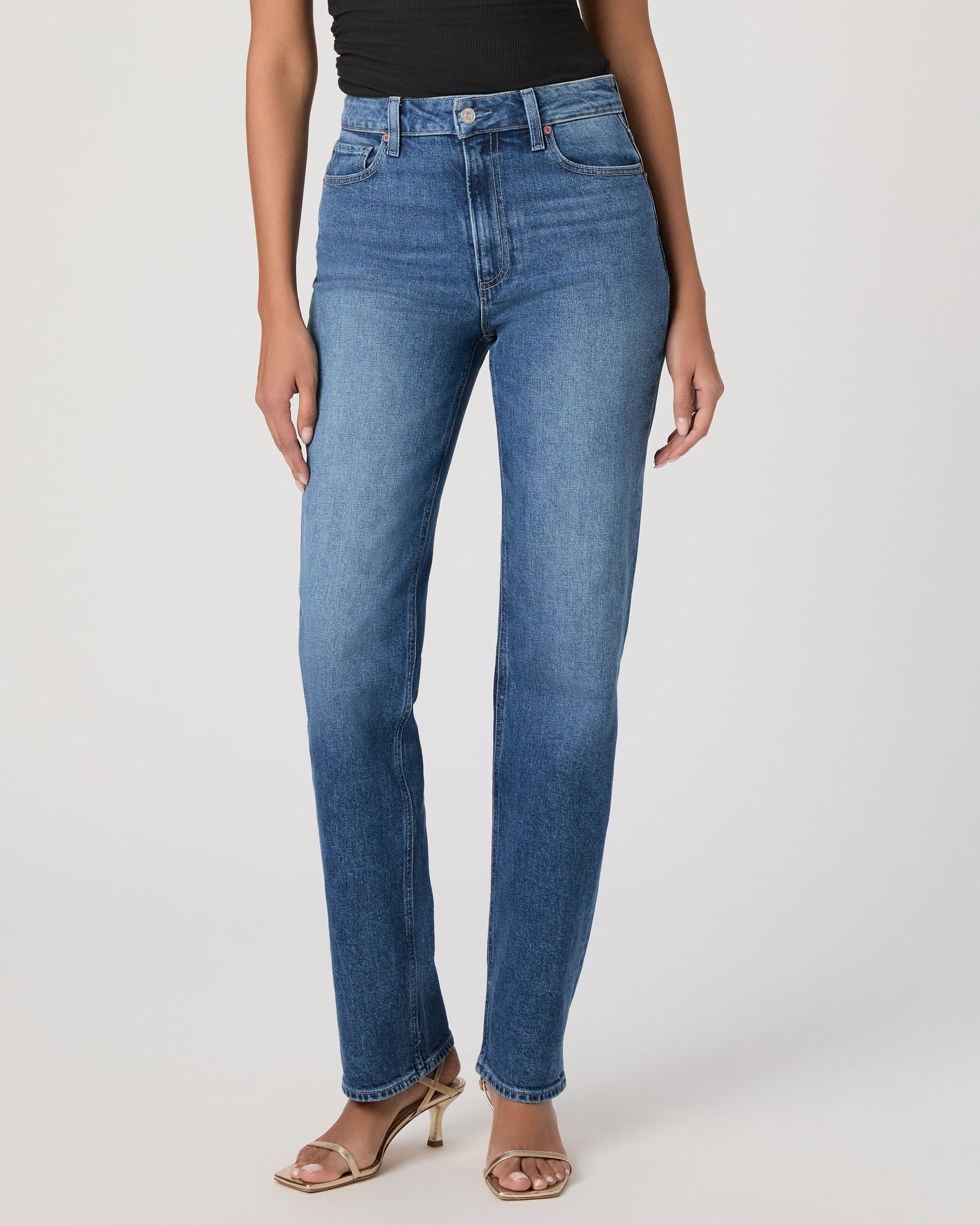 Woman wearing a black sleeveless top and blue jeans on a white background