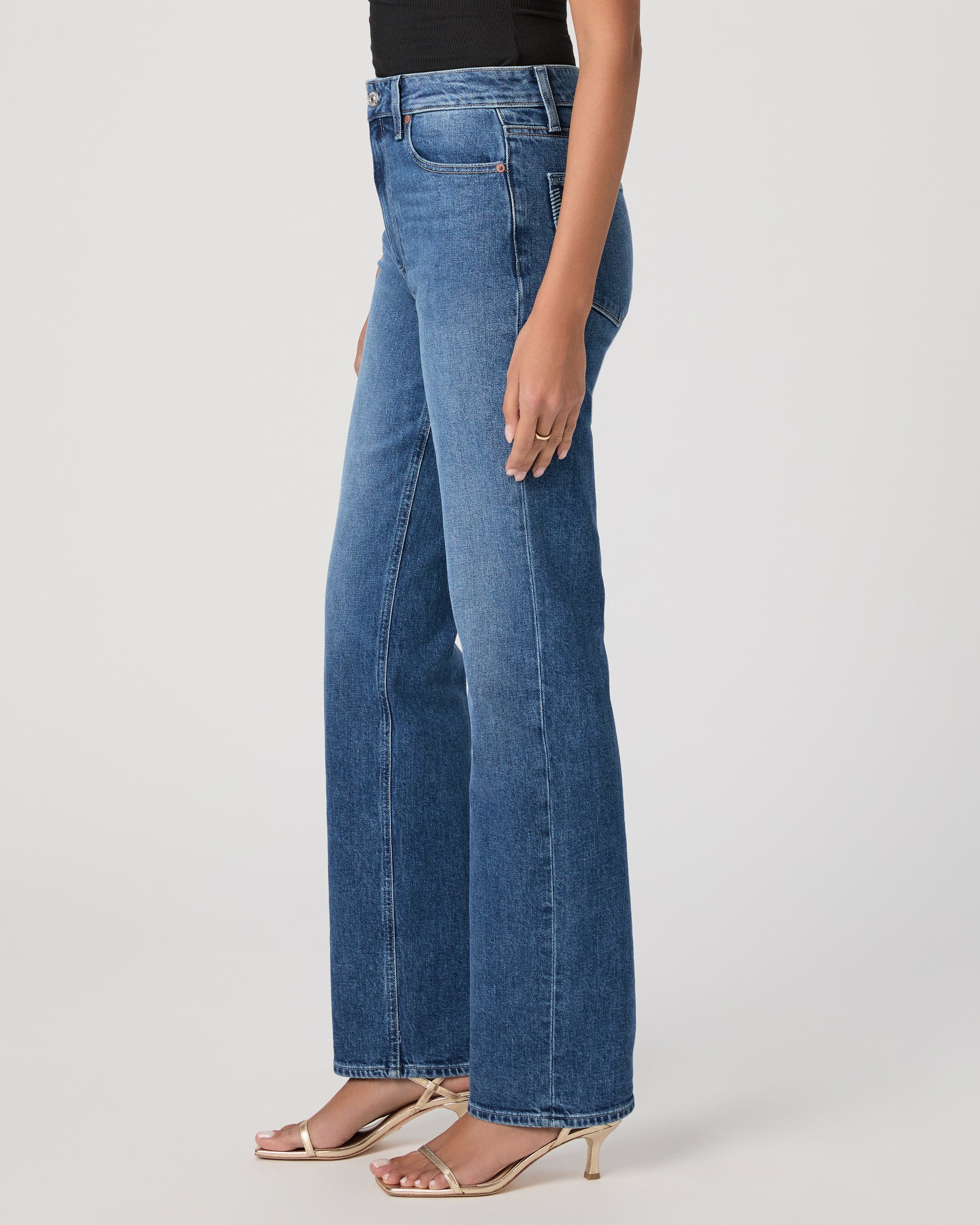 Woman wearing a black sleeveless top and blue jeans on a white background