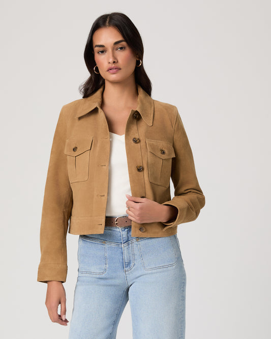 Woman wearing a brown jacket and light blue jeans on a plain background