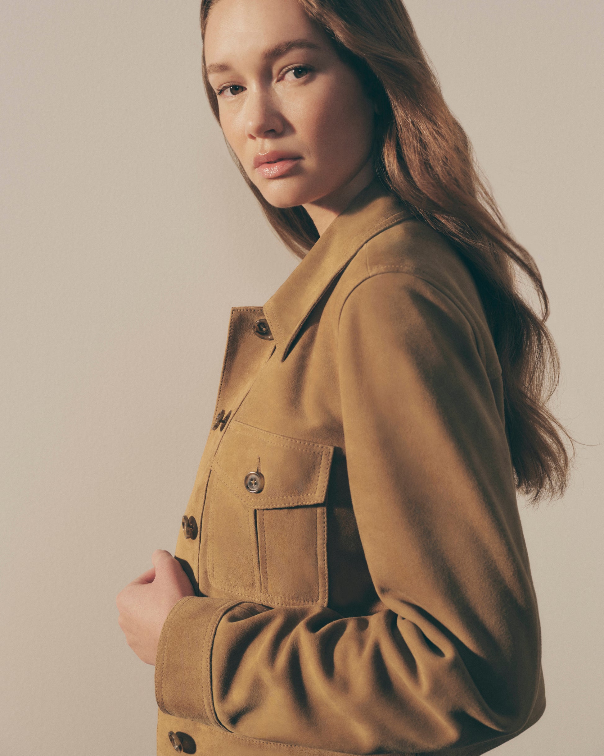 Woman wearing a brown jacket against a plain background