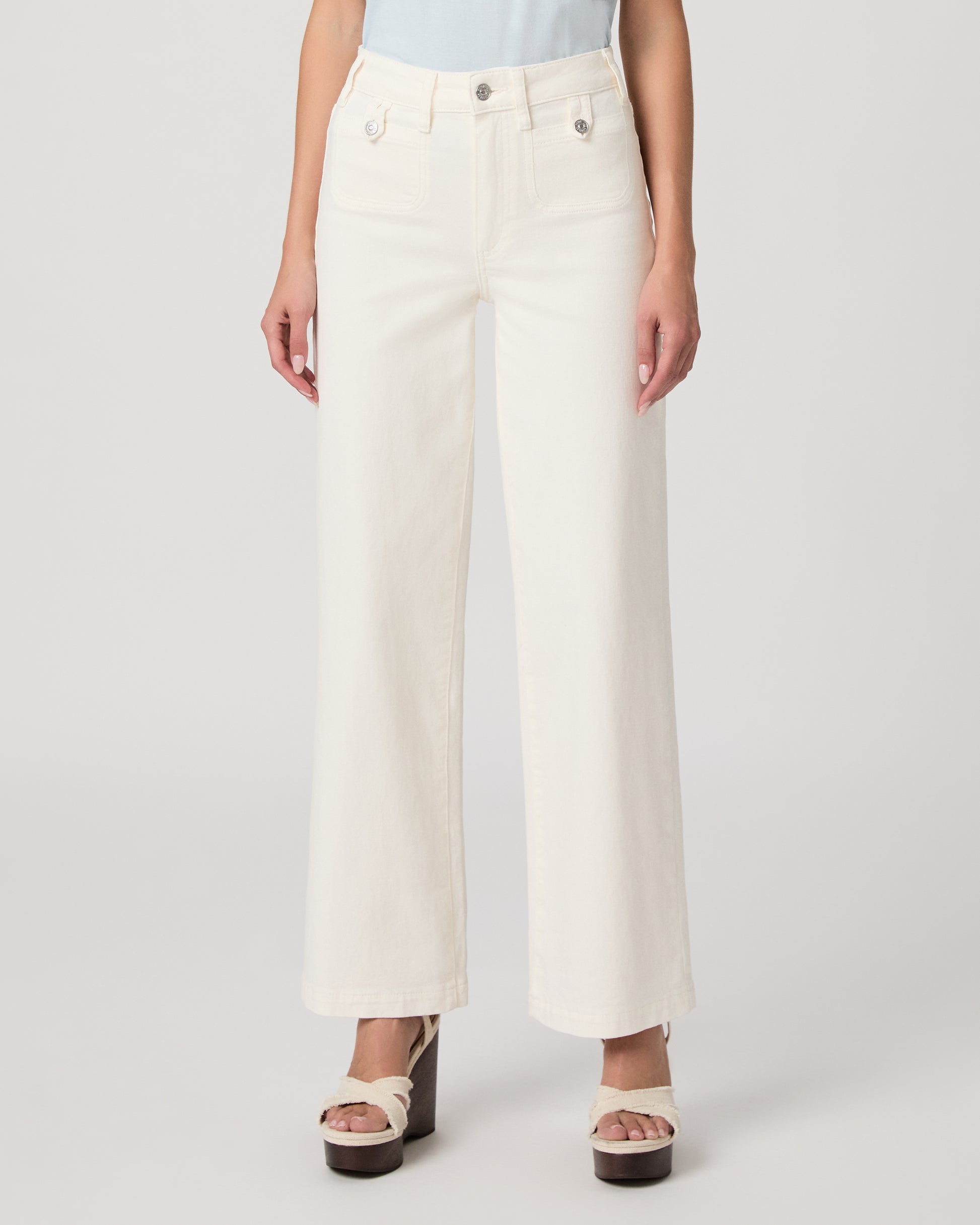 Woman wearing a light blue top paired with a white flare denim on a white background