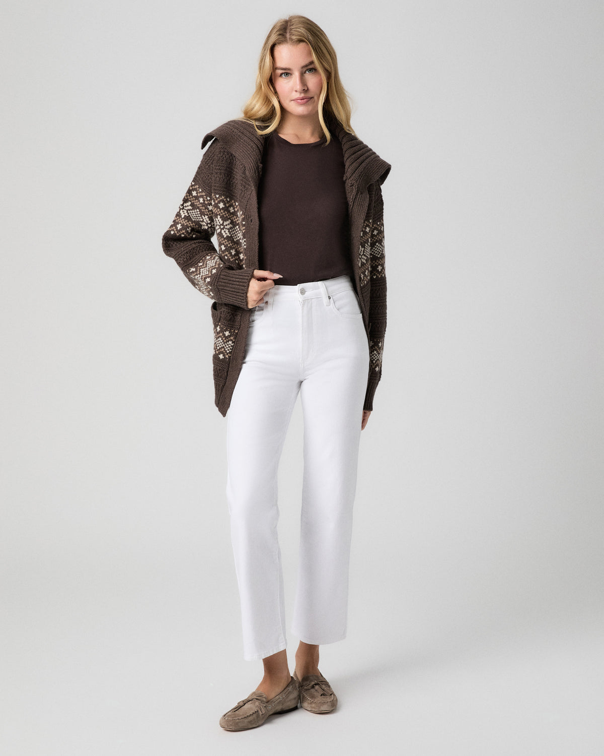 Model standing facing forward, one hand in her front pocket, wearing a brown patterned shawl-collar cardigan over a brown tee, Stevie Ankle Straight Jeans in Radiant White, and taupe loafers