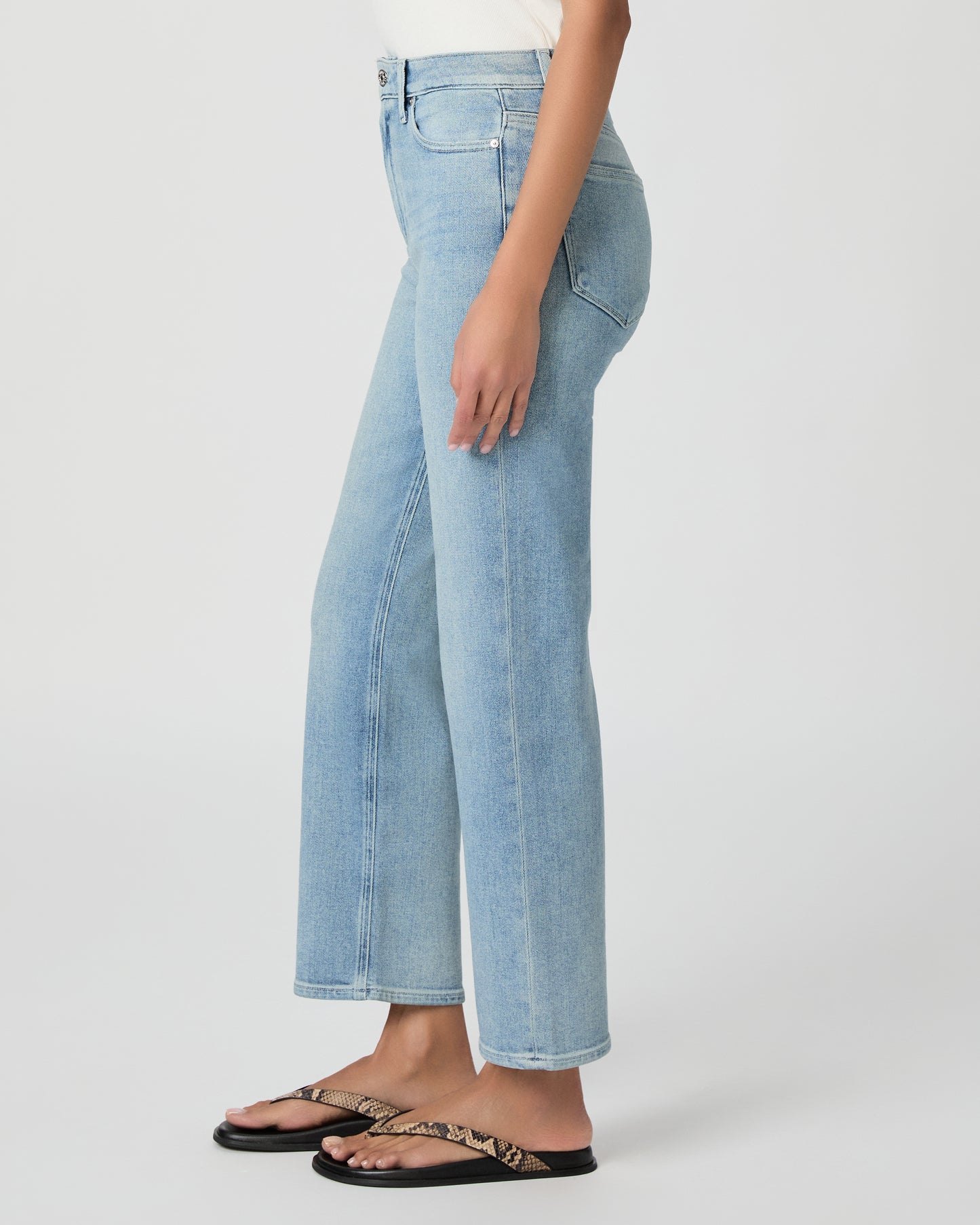 Woman wearing light blue jeans and a white top on a white background