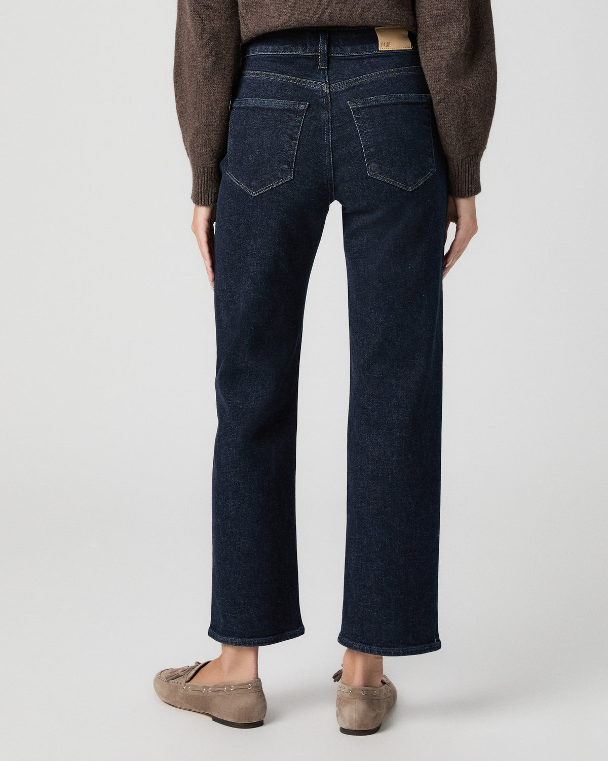 Back view from the waist down of the Stevie Ankle Straight Jean in Moderne dark wash, worn with a brown sweater and taupe suede loafers