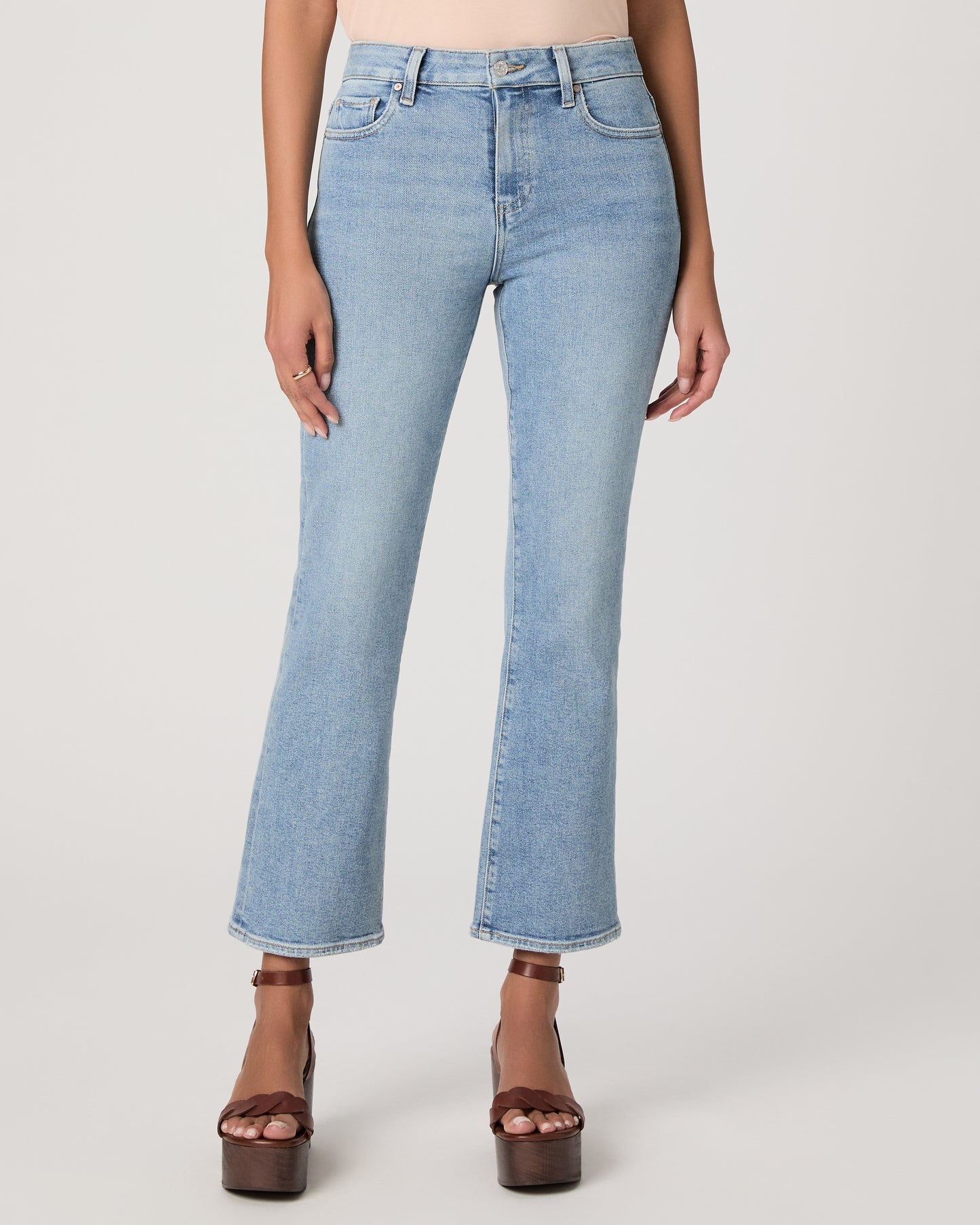 Woman wearing a beige top and blue jeans on a white background