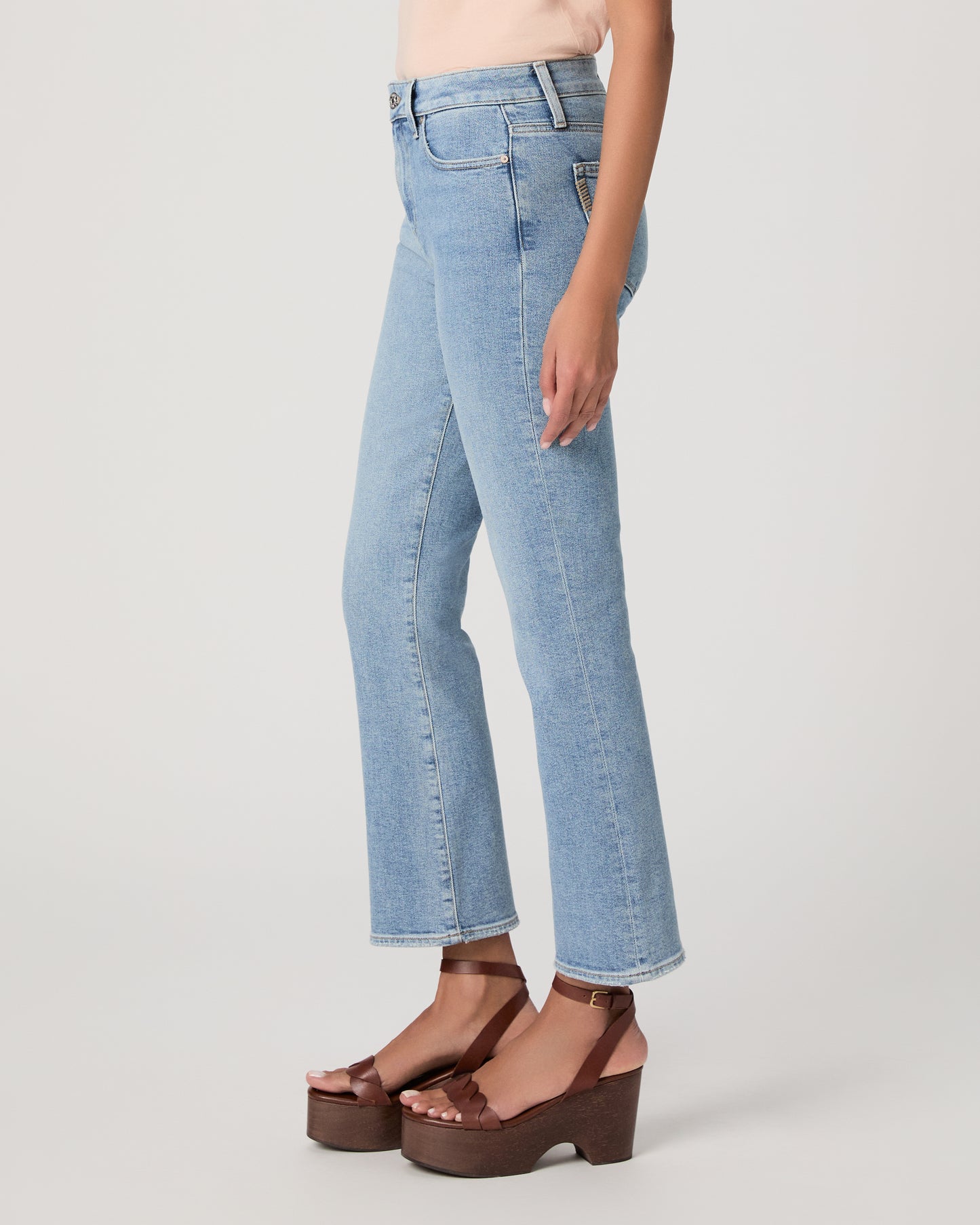 Woman wearing a beige top and blue jeans on a white background