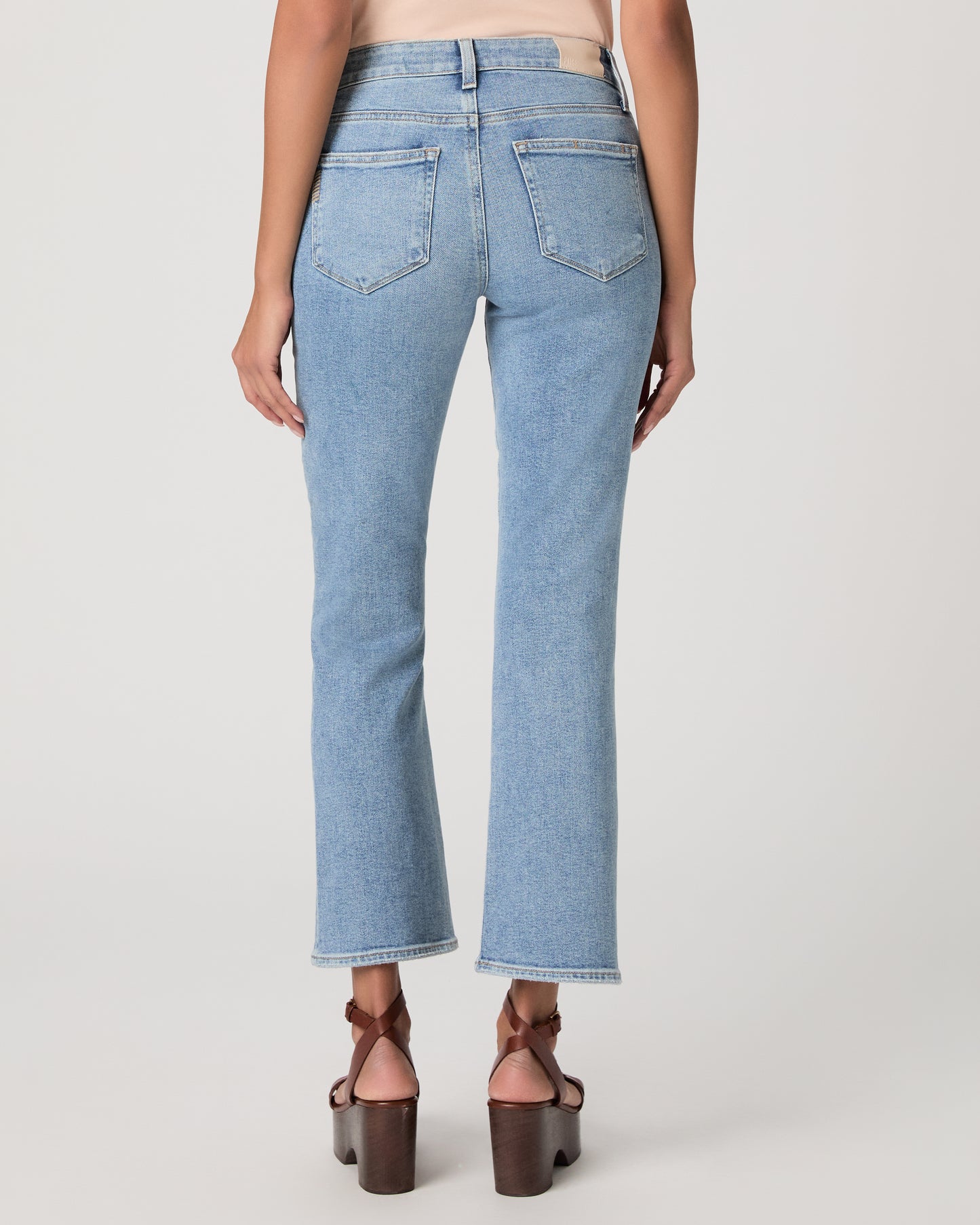 Woman wearing a beige top and blue jeans on a white background