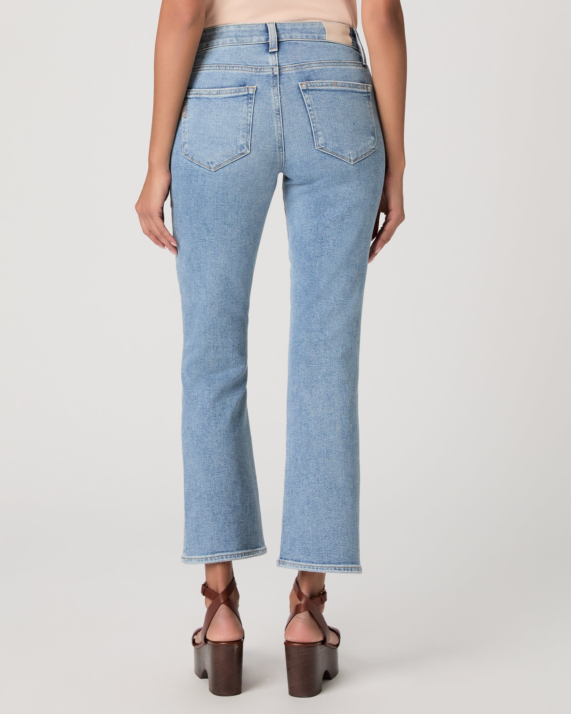 Woman wearing a beige top and blue jeans on a white background