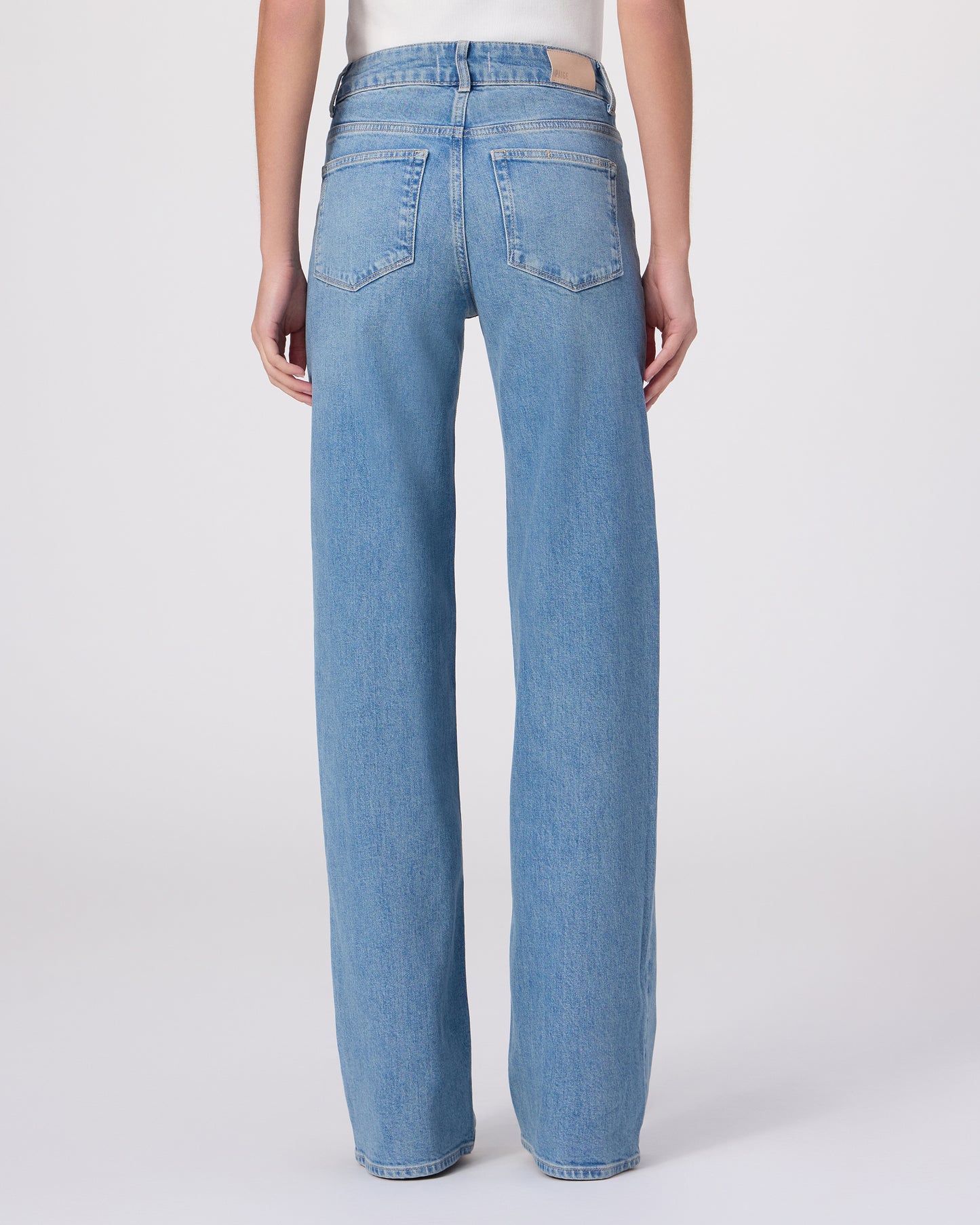 Woman wearing a white blouse and blue jeans on a white background