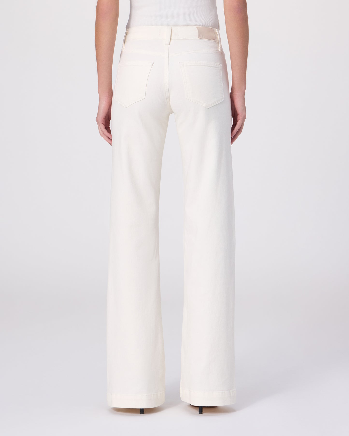 Woman wearing a white tee and white pants on a white background