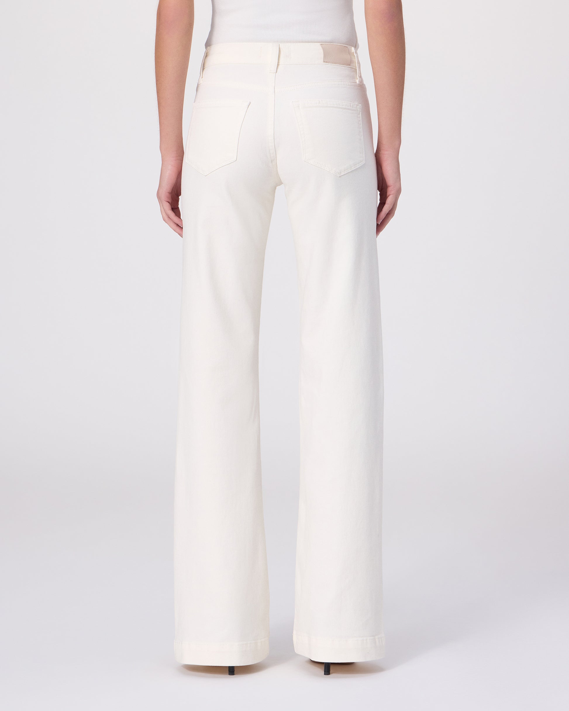 Woman wearing a white tee and white pants on a white background