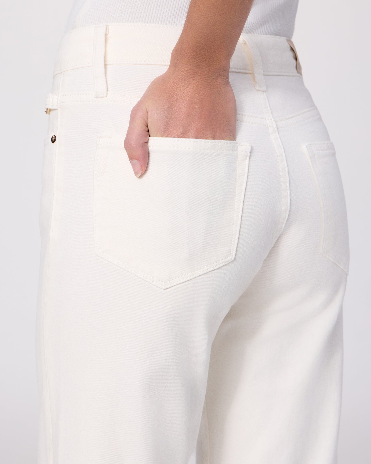 Woman wearing a white tee and white pants on a white background