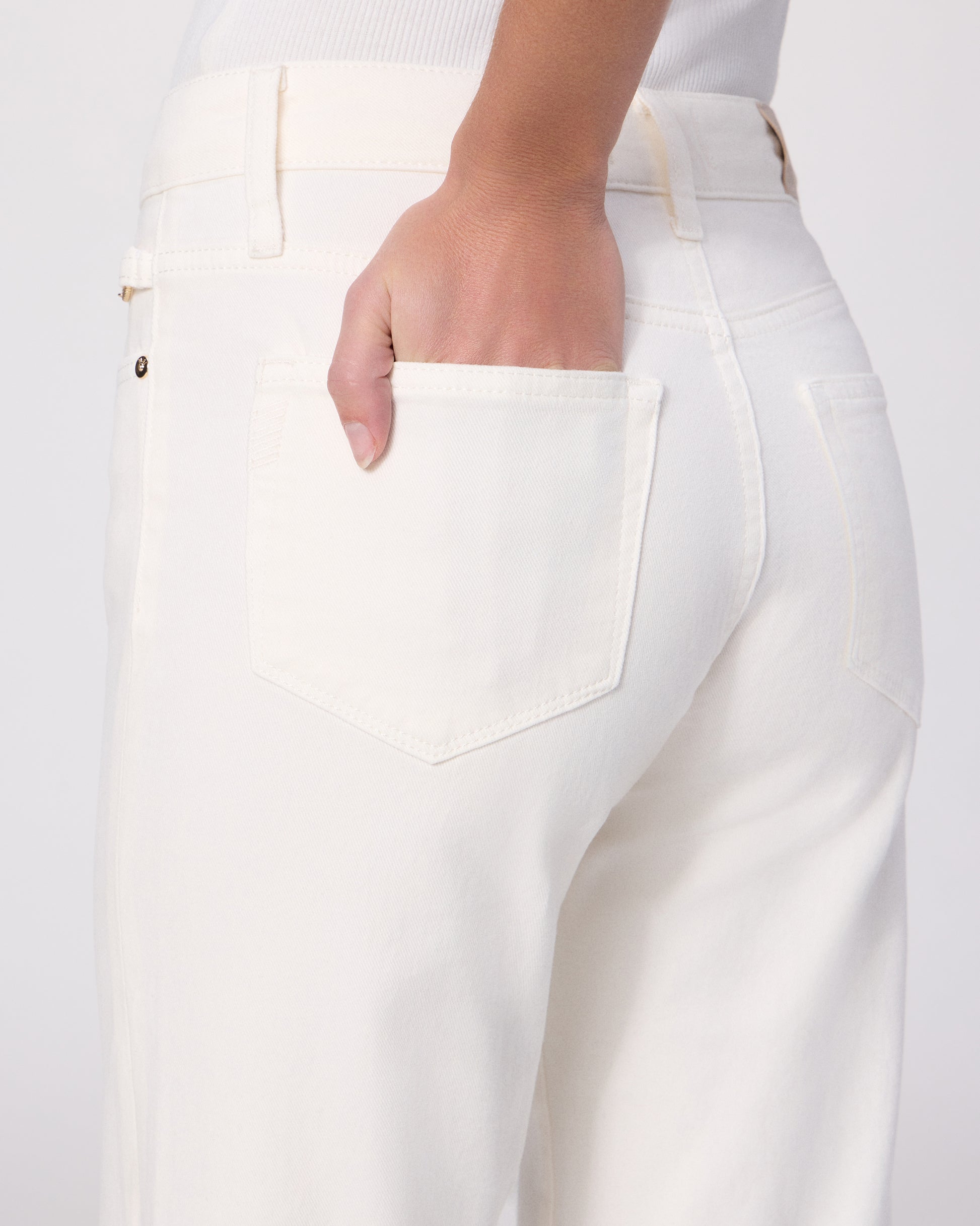 Woman wearing a white tee and white pants on a white background