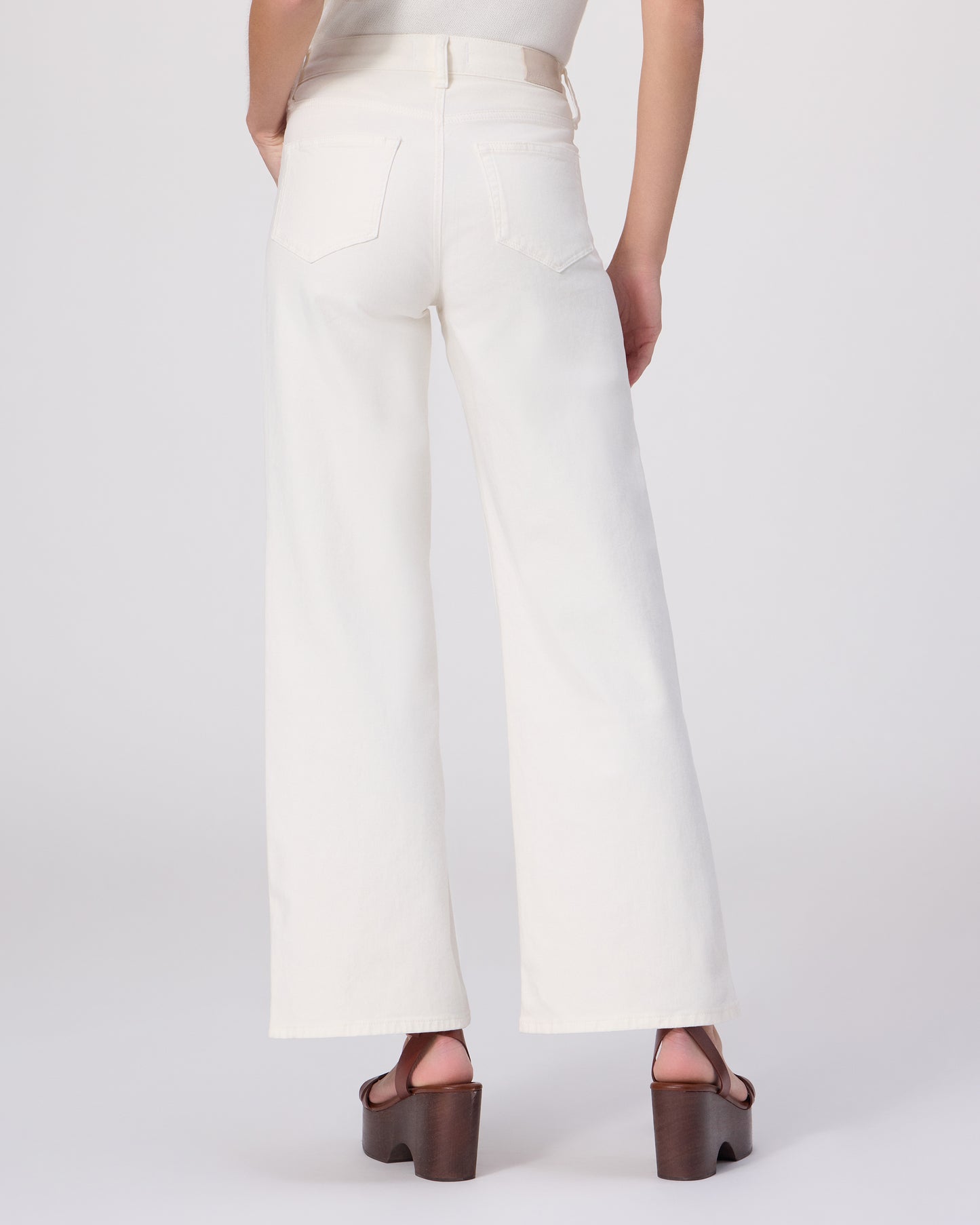 Woman wearing a white outfit with a brown belt on a white background