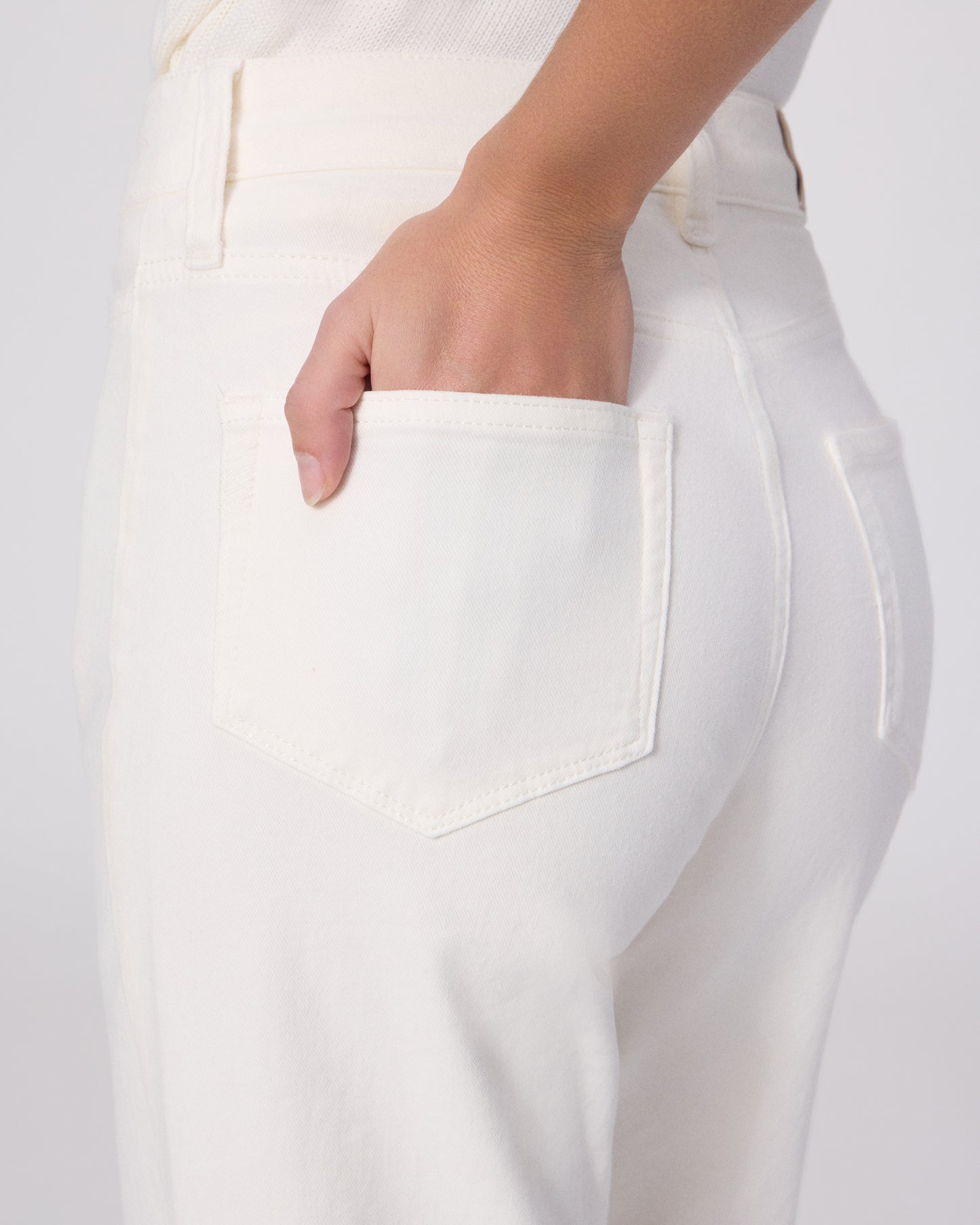 Woman wearing a white outfit with a brown belt on a white background