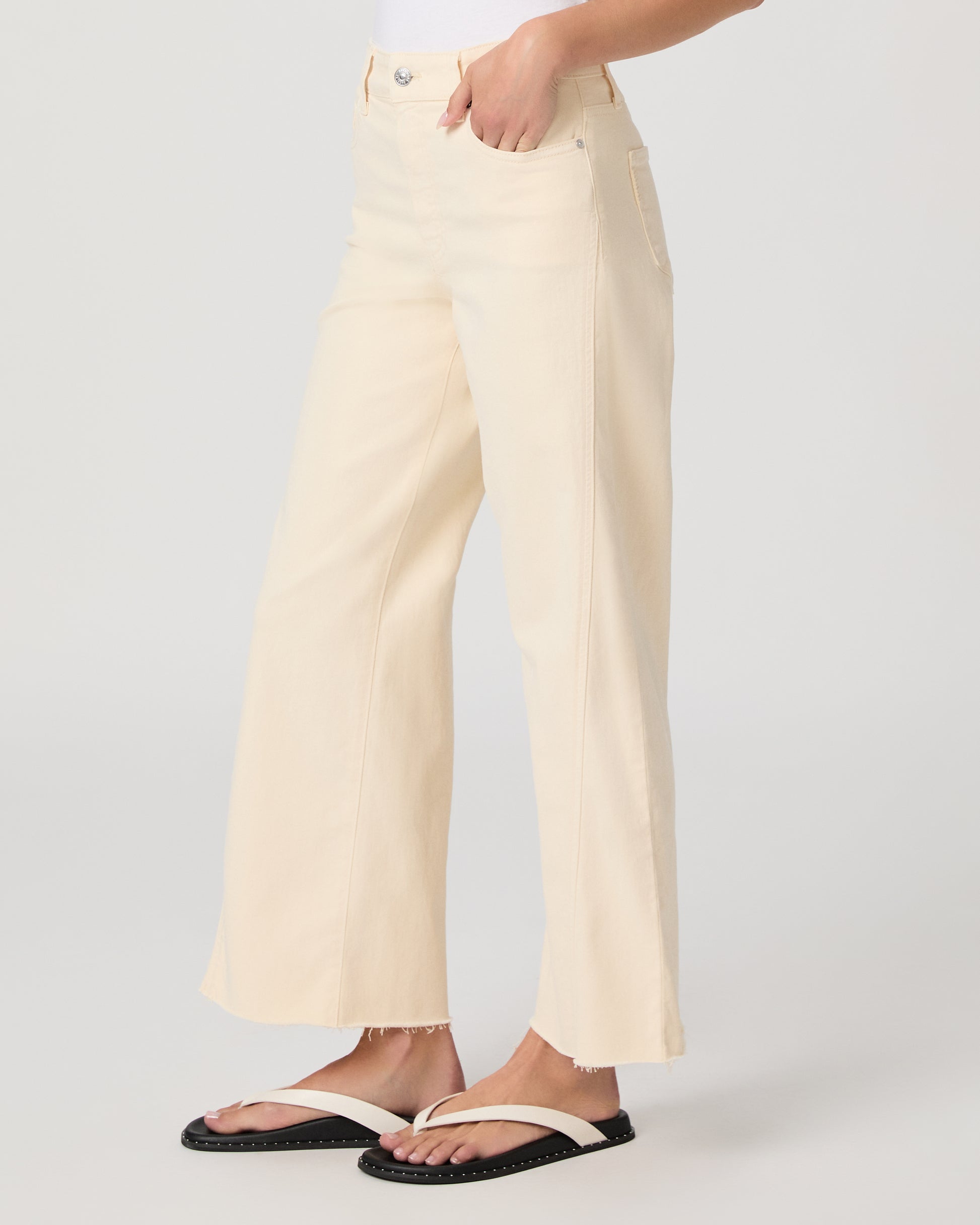 Woman wearing a white top and light yellow jeans on a white background