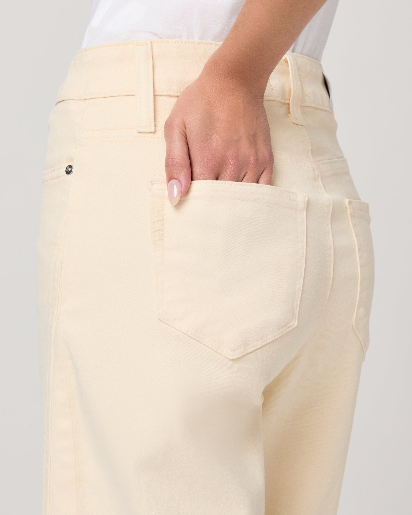 Woman wearing a white top and light yellow jeans on a white background