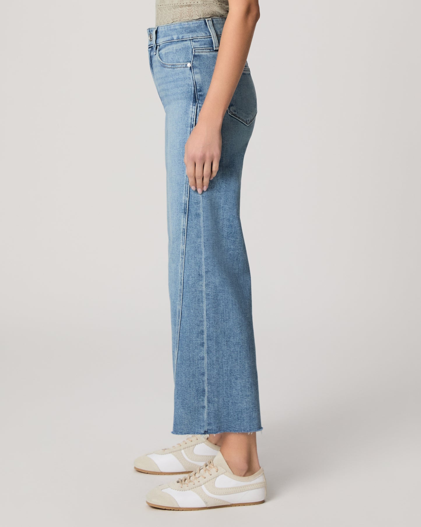 Woman wearing a light green top and blue jeans on a white background