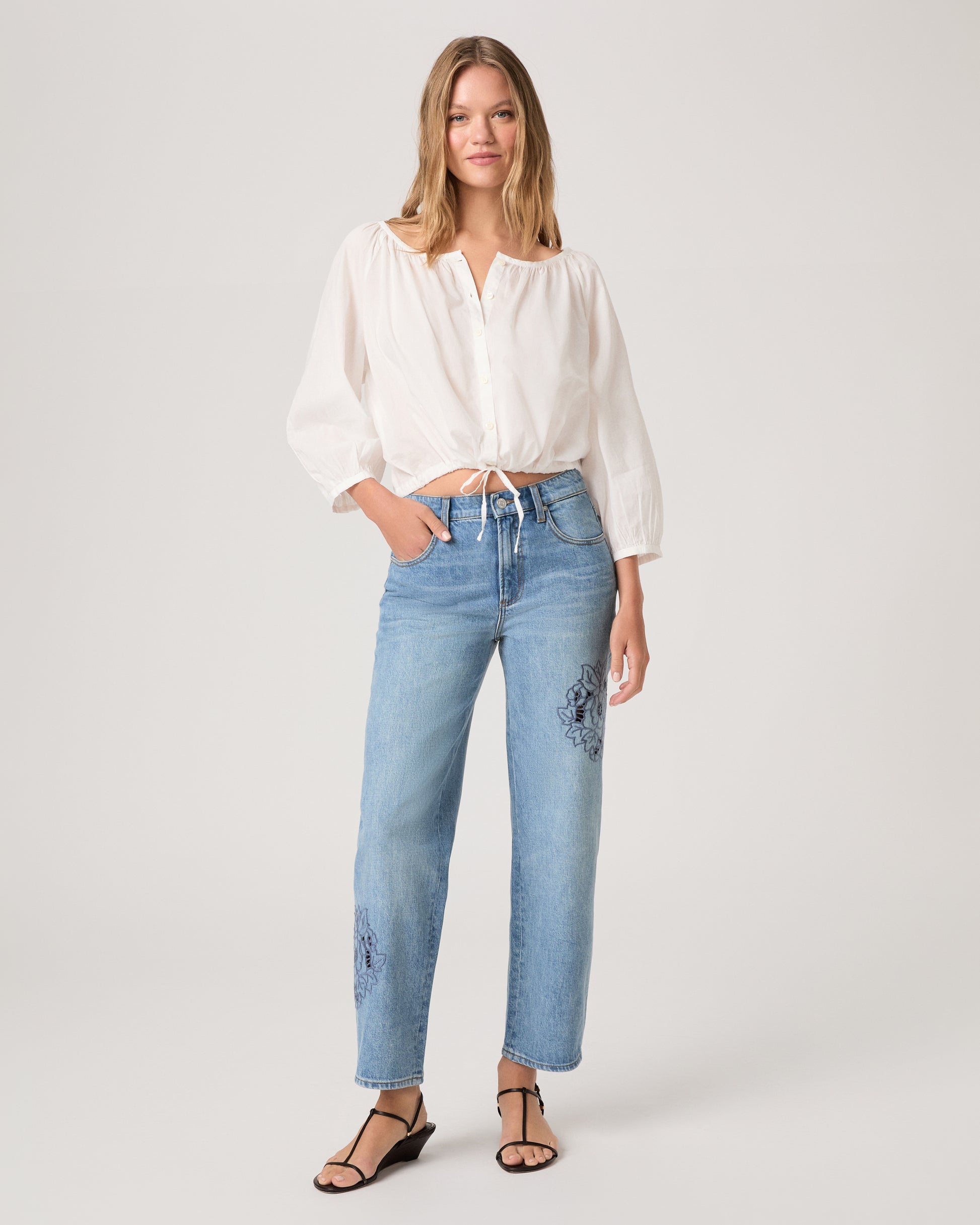 Woman wearing a white top and medium wash denim on a white background