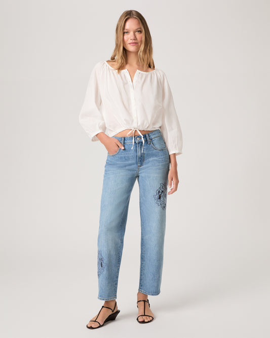 Woman wearing a white top and medium wash denim on a white background