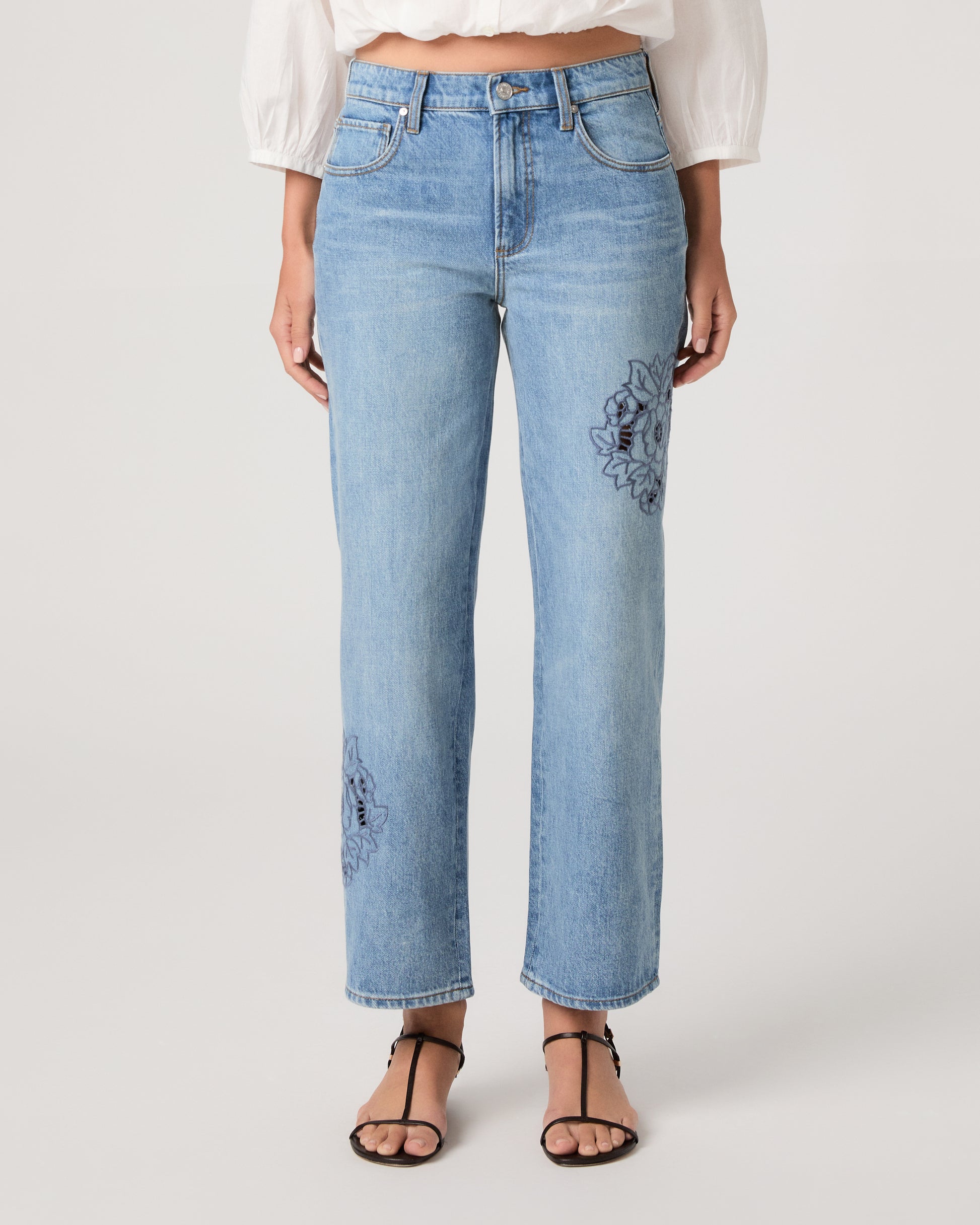 Woman wearing a white top and medium wash denim on a white background