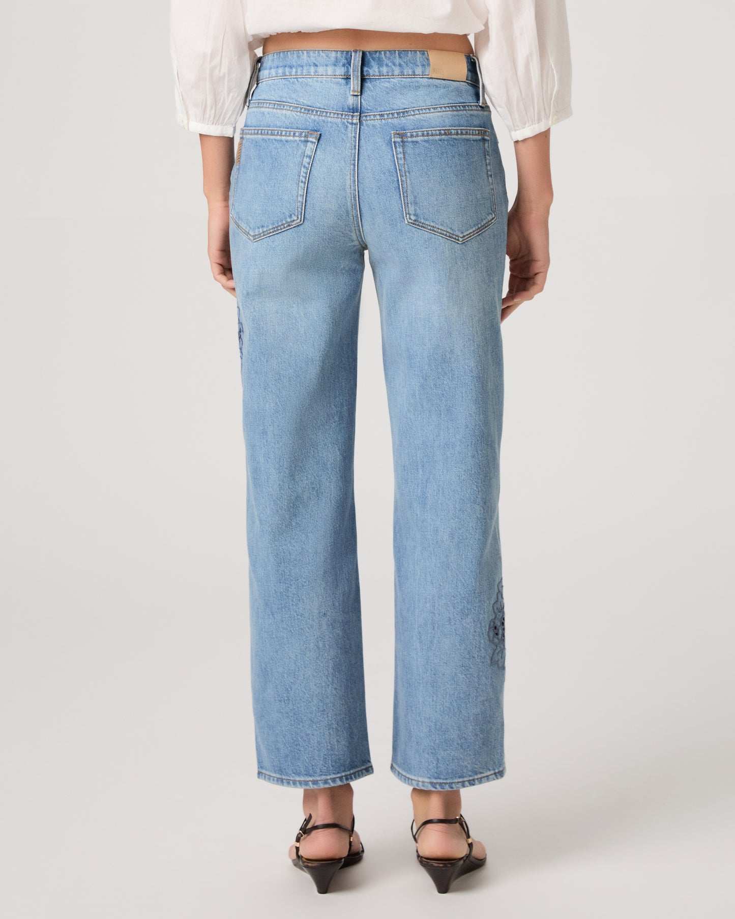 Woman wearing a white top and medium wash denim on a white background