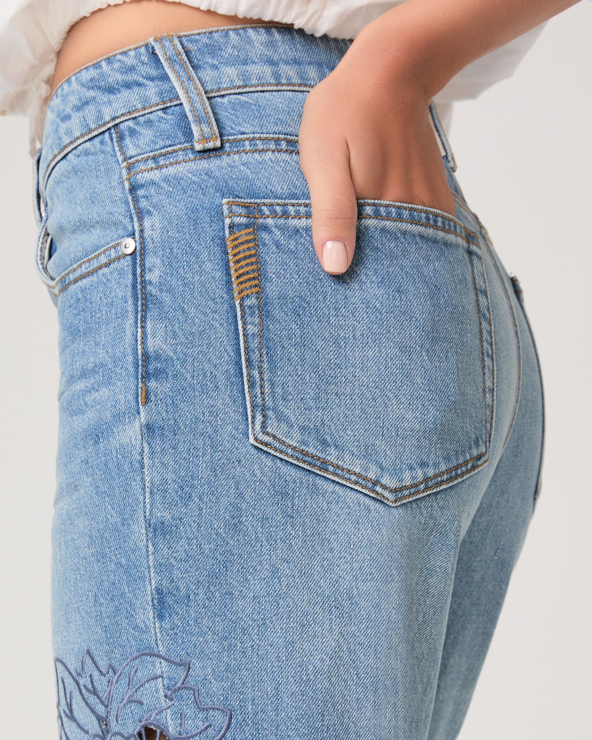 Woman wearing a white top and medium wash denim on a white background