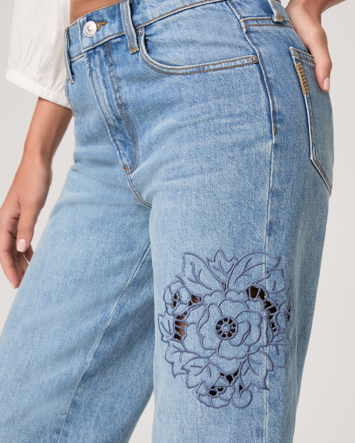 Woman wearing a white top and medium wash denim on a white background