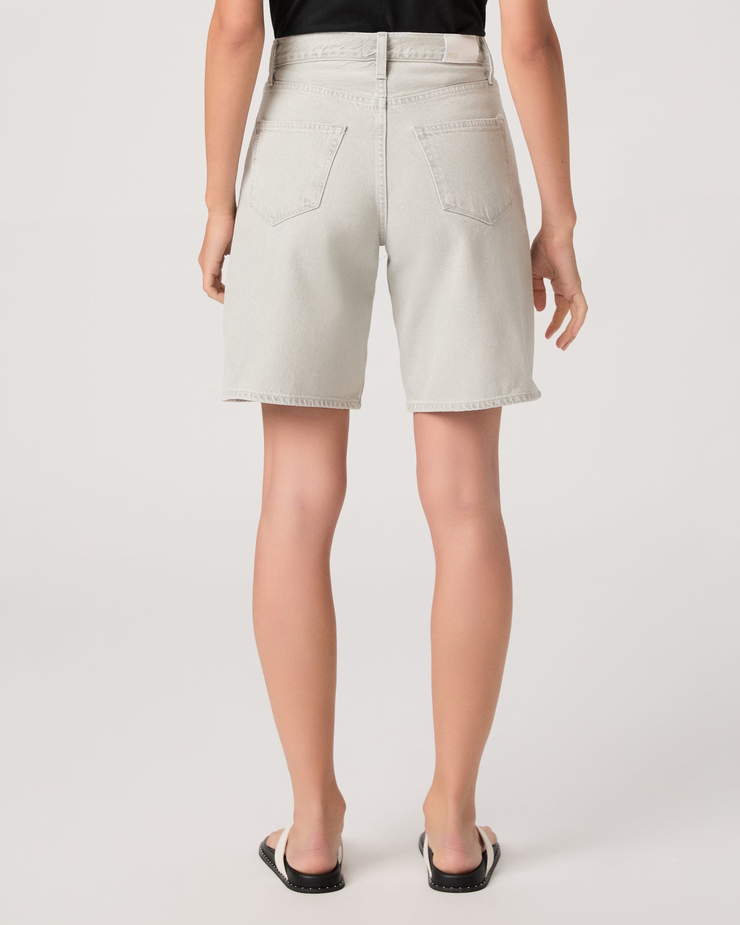 Woman wearing a black top and grey shorts on a white background