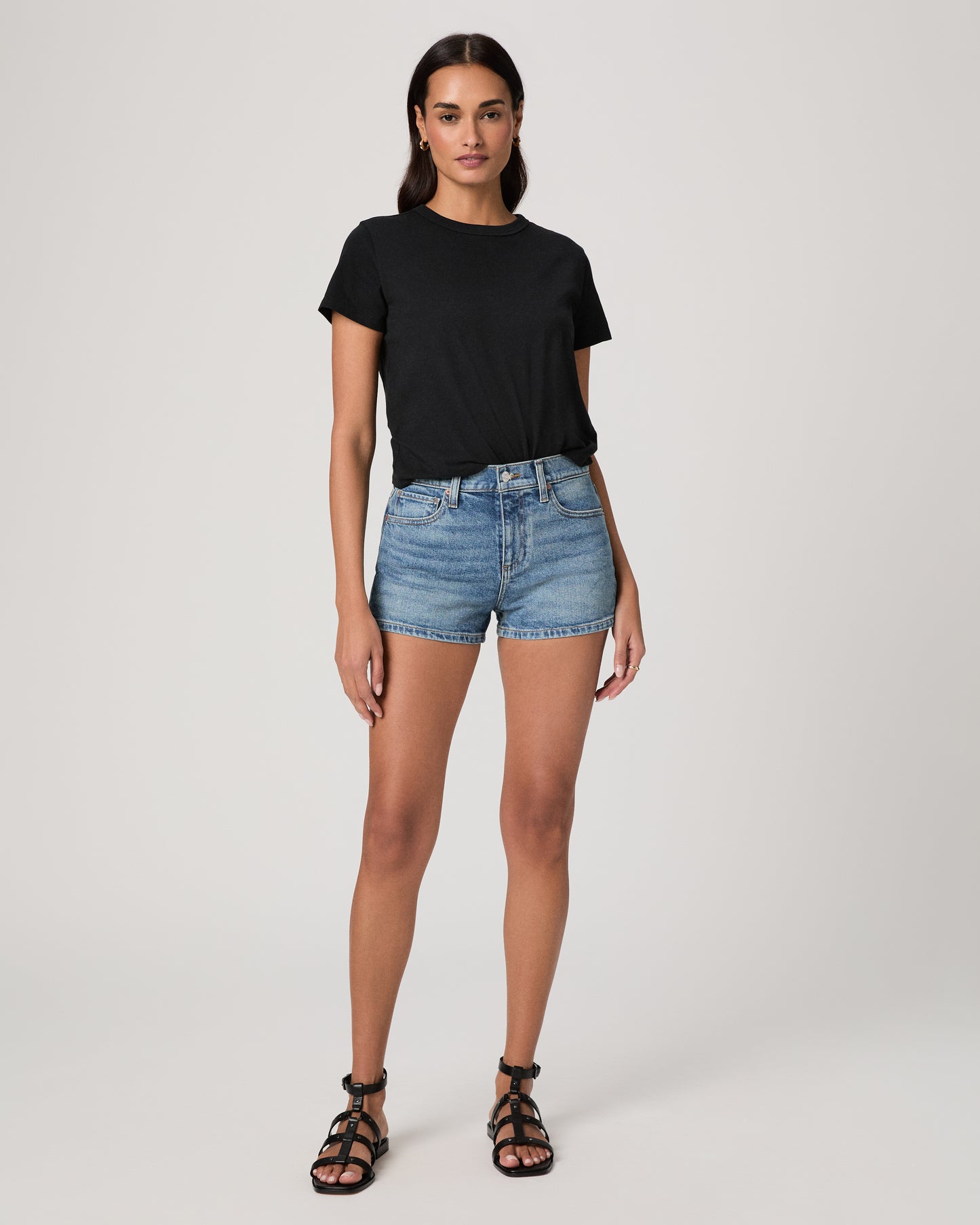 Woman wearing a black t-shirt and denim shorts on a white background