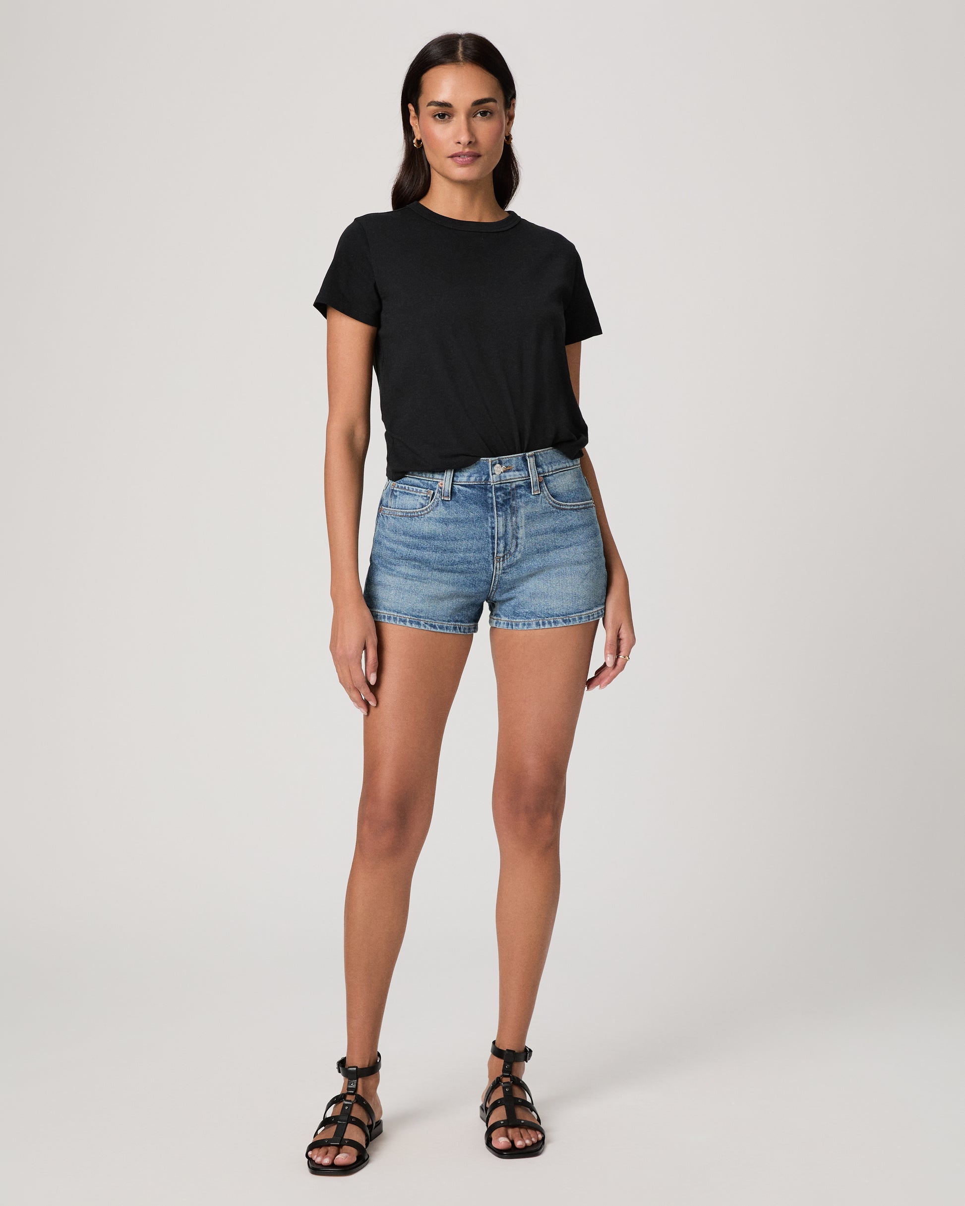 Woman wearing a black t-shirt and denim shorts on a white background