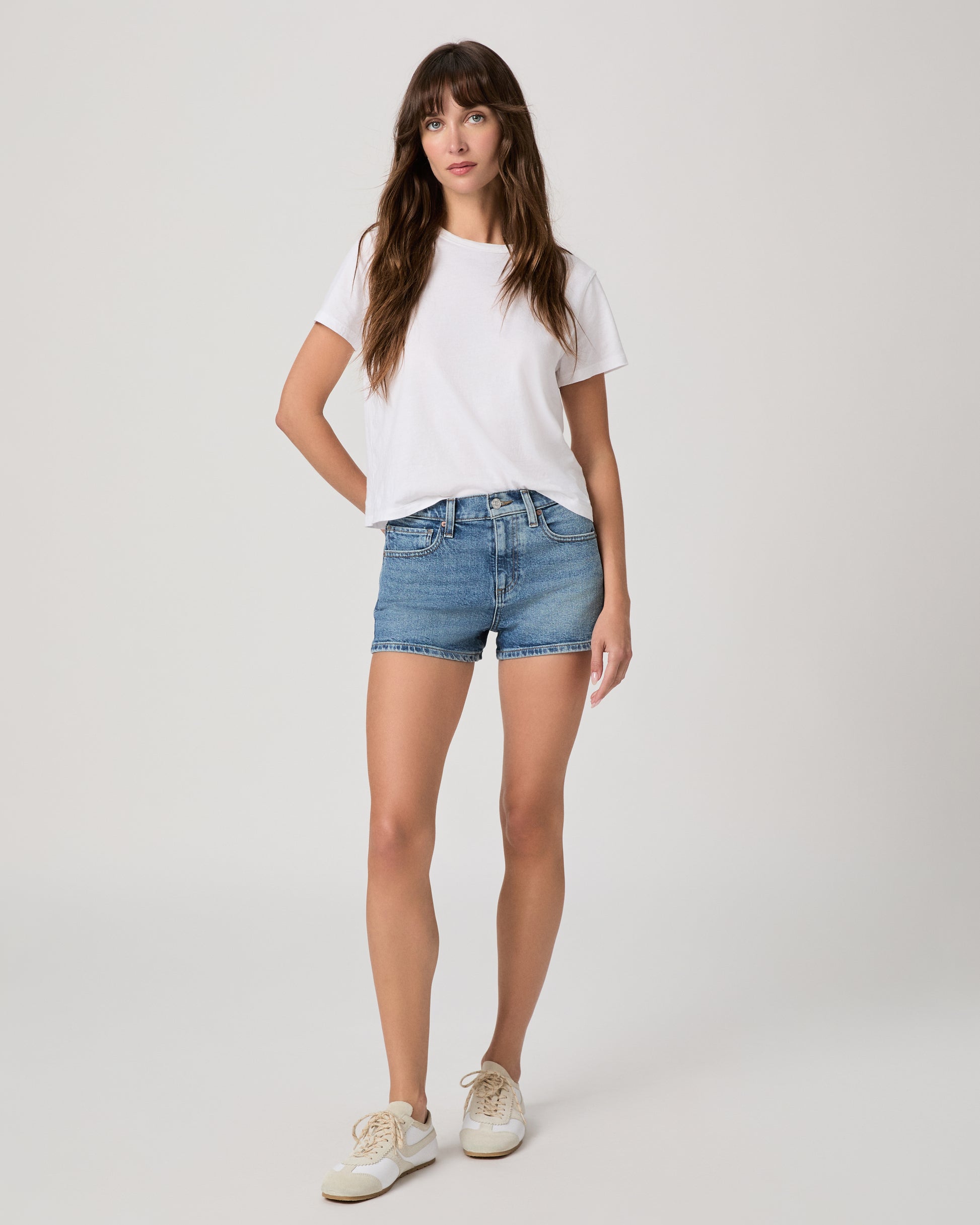 Women wearing white tee, blue shirts paired with white sneakers against a white background 