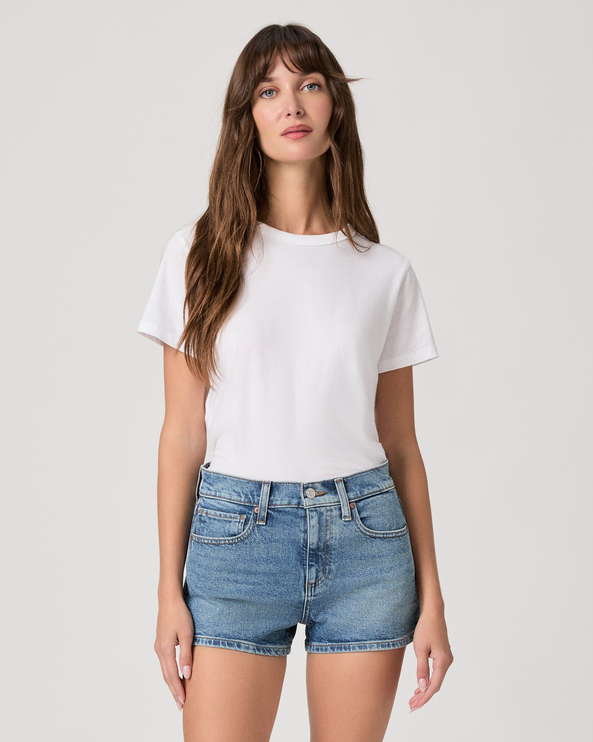 Women wearing white tee, blue shirts paired with white sneakers against a white background 
