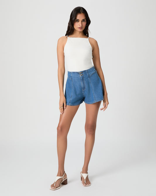 Woman wearing a white top and blue denim shorts on a white background