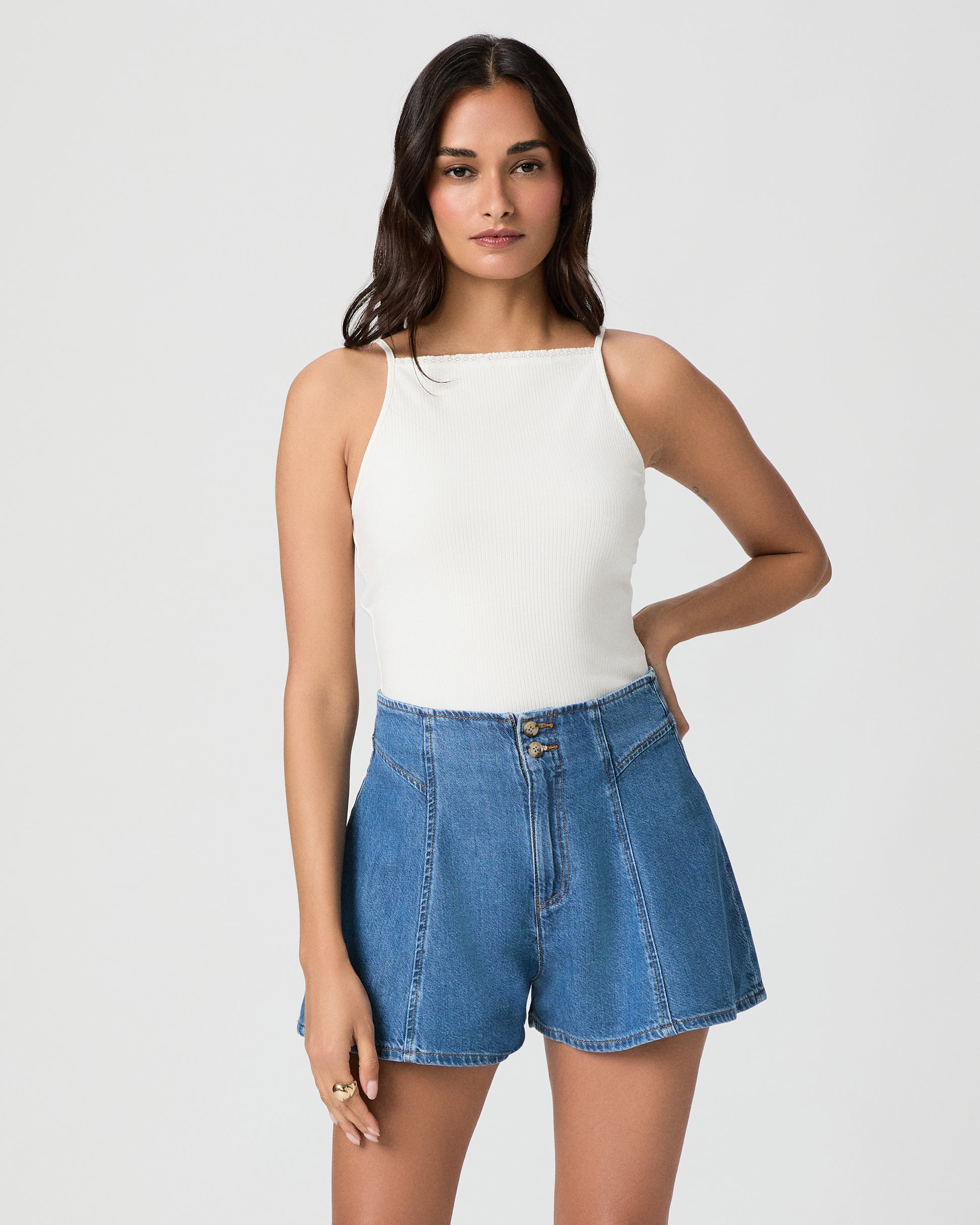 Woman wearing a white top and blue denim shorts on a white background