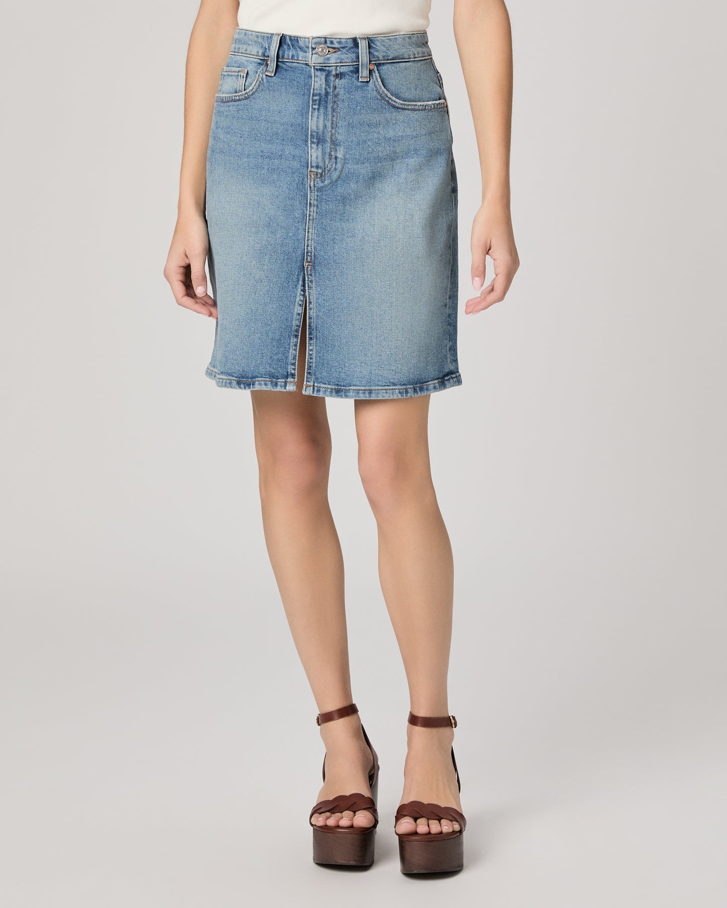 Denim skirt worn by a person on a plain background